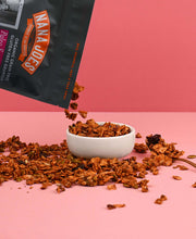 Load image into Gallery viewer, Nana Joes Granola Paleo Sunrise Cranberry blend granola pouring into a white bowl on a pink background