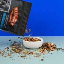 Load image into Gallery viewer, Nana Joes Granola bag spilling into a white bowl on a blue background.
