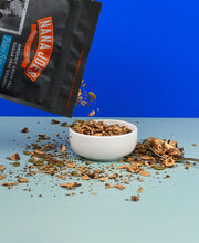 Load image into Gallery viewer, Nana Joes Granola Paleo Sunrise Hazelnut Keto Blend pouring into white bowl on two-tone blue background

