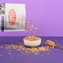 Load image into Gallery viewer, Nana Joes Granola bag spilling into a white bowl on a purple background.
