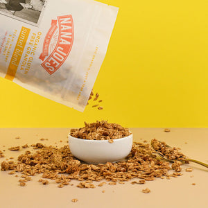 Nana Joes Granola bag spilling into a white bowl on a yellow background.