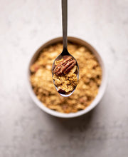 Load image into Gallery viewer, Spoonful of granola with a pecan on a light background
