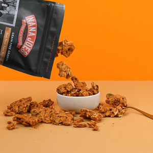 Nana Joes Granola bag spilling into a white bowl on an orange background.